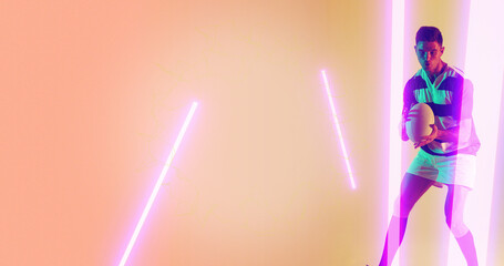 Caucasian male player holding rugby and standing by illuminated lines over peach background