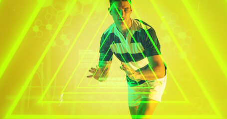 Caucasian rugby player standing over illuminated yellow triangles computer language and hexagon