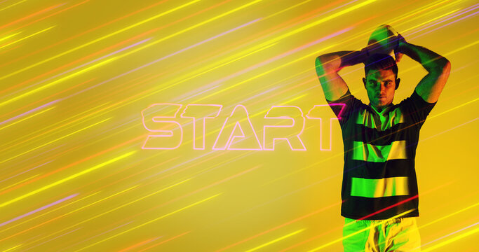 Caucasian rugby player throwing ball by illuminated start text over colorful long exposure