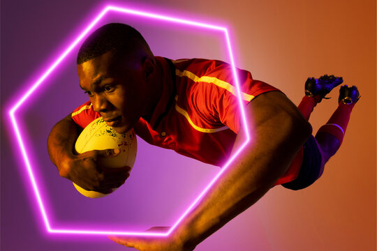 Hexagon neon over african american young rugby player jumping against colored background - Powered by Adobe