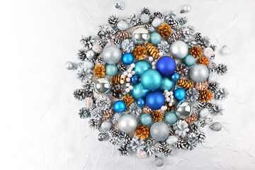 Christmas wreath with blue balls and golden cones on silver background