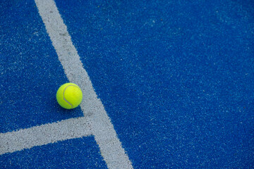 a ball on a blue paddle tennis court where the lines meet