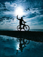 silhouette of a guy on a mountain bike against the background of the sea and beautiful textures of...