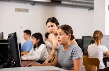 Obraz premium Woman teacher helps girl with learning on computer in school class