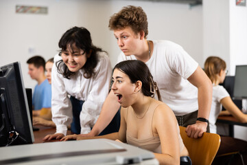 Positive young boy and girls using personal computer together. Cheerful teenagers in computer class.