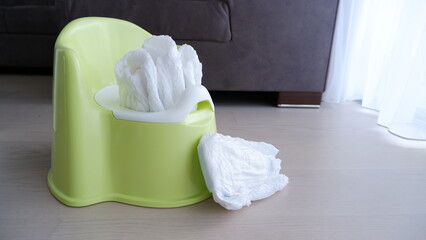 Diapers inside and near baby green plastic potty at home