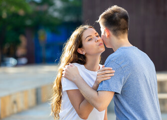 Obraz premium Young man and girl are hugging and kissing each other in cheek