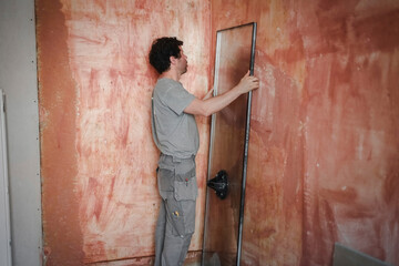 Obraz na płótnie Canvas Caucasian man rests a window pane against a wall in a room.