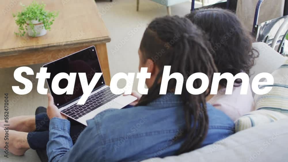 Poster Animation of stay at home text over biracial couple using laptop