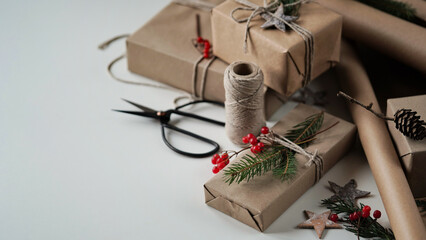 Fototapeta na wymiar Zero waste and eco friendly christmas concept. Christmas and New Year gifts for family and friends wrapped in brown paper, rope and natural plant decor, copy space, space for text. Selective focus.