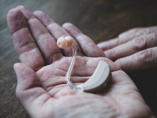 Hearing device in hand of elder person. World hearing day