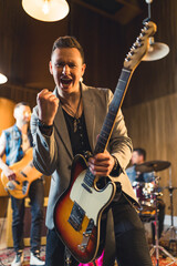 Energized man with an electric guitar during a music band performance. High quality photo
