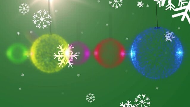 Animation of snow falling over christmas boubles on green background