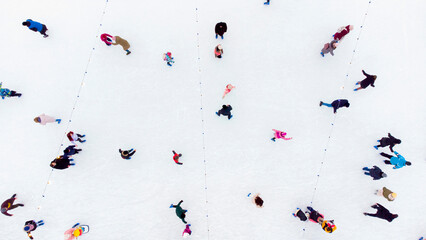 People Skating on an Open-Air Ice Skating Rink. Top view. Many People Skating on Ice of Rink. Aerial Drone View. Beautiful Skating Sport and Winter Outdoor Activities Background