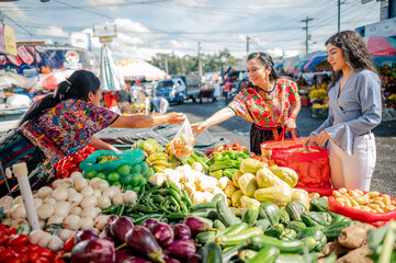 Madre e hija comprando verduras frescas en un mercado de Quetzaltenango, Guatemala.