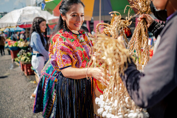 Mujer guatemalteca comprando a un vendedor de un mercado local.
