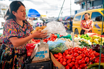 Mujer indígena vendiendo vegetales en un mercado guatemalteco. 
