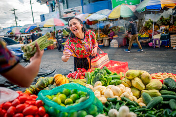 Retrato de Una Mujer feliz comprando espárragos frescos en un mercado local. 