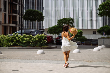 Beautiful pretty woman in white dress walking at city street