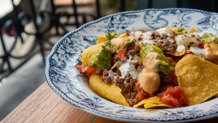 Corn chips nachos with fried minced meat and guacamole on wooden background.