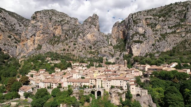 Beautiful french village Moustiers-Sainte-Marie beneath a mountain France aerial shot sunny day 
