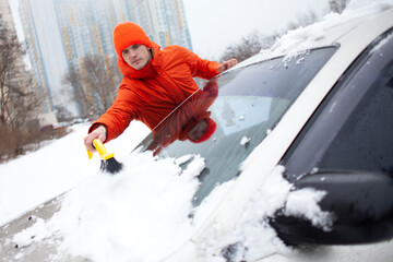 guy cleans the snow with a brush from the car, a man takes care of the car in winter