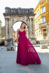 Beautiful young woman in a long dress enjoys a walk in the old part of the city