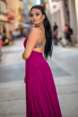 Fototapeta premium Beautiful young woman in a long dress enjoys a walk in the old part of the city