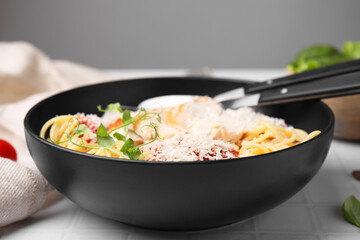 Delicious pasta with tomato sauce, chicken and parmesan cheese on white tiled table, closeup