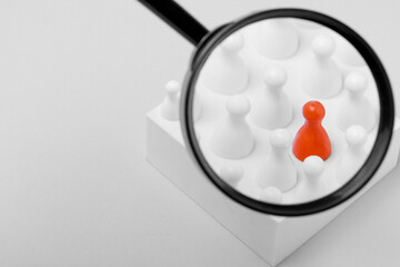Magnifying glass over pawns on white background, space for text. Recruiter searching employee