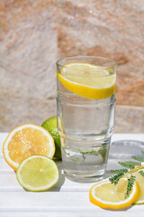 Delicious refreshing lemonade and pieces of citrus on white wooden table outdoors