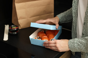 Woman unpacking her order from sushi restaurant at countertop in kitchen, closeup