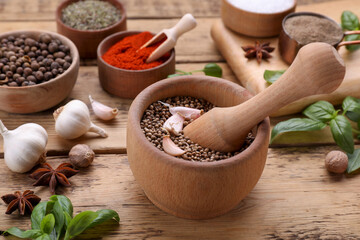 Mortar with pestle and different spices on wooden table