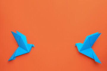 Beautiful light blue origami birds on orange background, flat lay. Space for text