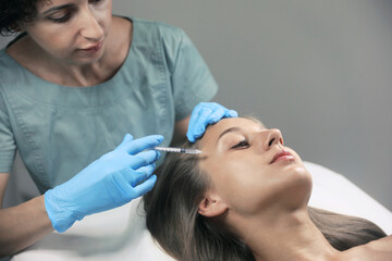 Obraz na płótnie Canvas Beautiful woman getting facial injection in salon