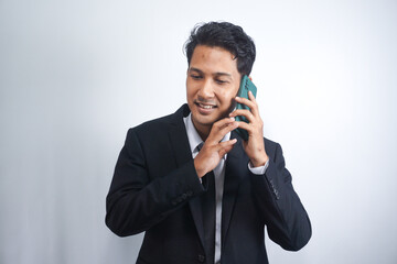 Young Asian Man is confused and shocked when calling in the phone. Indonesian man wearing a black suit.