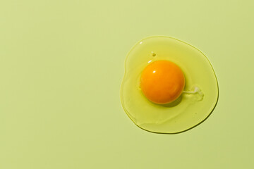 Raw egg yolk on a green background. View from above - obrazy, fototapety, plakaty