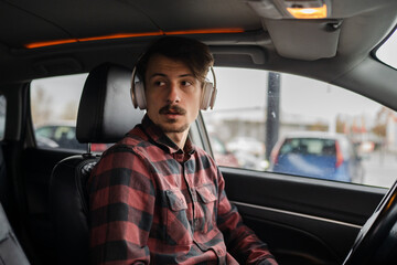 man with headphones listen music or podcast in car use mobile phone