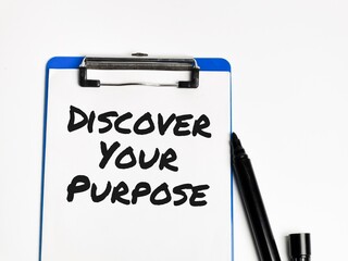 Phrase discover your purpose written on paper clipboard against white background.