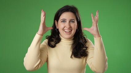 Fototapeta premium Pretty thinking young woman 20s, looks at camera gives mind blown gesture showing explosion of ideas posing on green screen background.