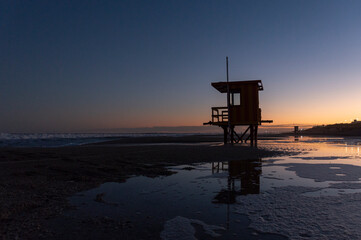 A lifeguard stand on the beach by the sea at dusk almost at night, in Pinamar, Buenos Aires,...