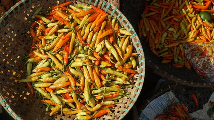 Red chili on a bamboo basket in a traditional market. Exposed to the morning sun. Selected focus