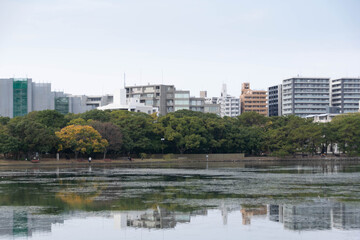 Obraz na płótnie Canvas view of city town skyline over the pond lake natural view under daytime in japan, big city with natural lake public