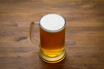 A large mug of light tasty cold beer on a wooden table, close-up, rustic style