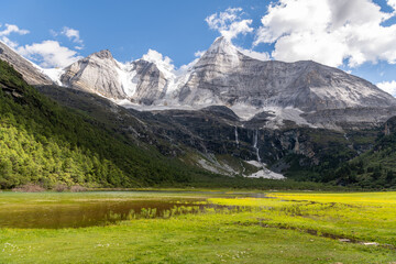 Gorgeous pasture in Daocheng Yading, China. Traveling to Daocheng Country and Yading Nature Reserve, you will find pastures full of flowers, gurgling streams, simple villages and tall mountains
