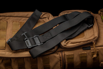 A black nylon weapon belt on a brown military backpack. Dark back.