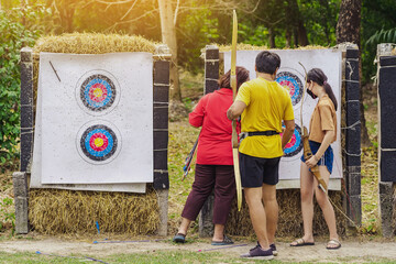 Back view of Asian archers wear face mask collect arrows fired from a bow on sport target. Archer...