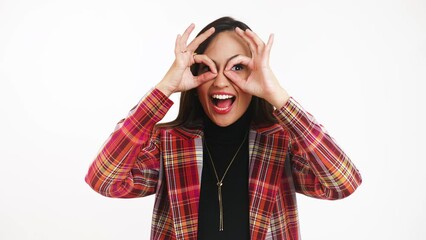 Portrait of a happy young woman making circles using her hands around her eyes and smiling at the camera, isolated. High quality 4k footage - Powered by Adobe