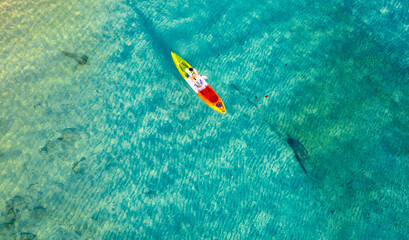aerial view woman kayaking on the island of andaman View of the top view of the blue sea, see the rocks under the water. She does water sports activities.