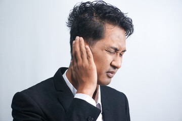 Unhealthy young asian man suffering from sudden throbbing ear ache.
